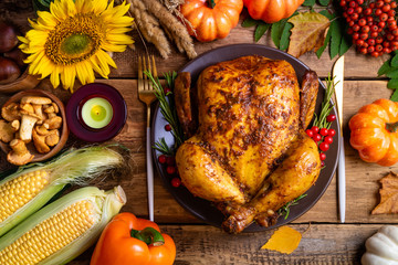 Baked chicken for Thanksgiving Day. Roasted whole chicken or turkey with autumnal vegetables, mushrooms and berries for thanksgiving dinner on wooden table. Thanksgiving Day concept. Top view