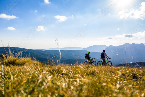 Aerial view. Epic shot of two mountain bikers on top of the mountain looking down the valley. Aerial shot of mountain biker on the top looking at amazing view in the autumn. mountain bike. bycicle