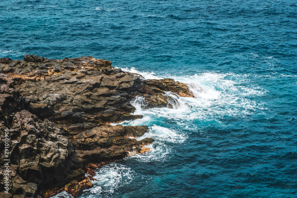 black rock in surf, cliff in oceran - rocky coast