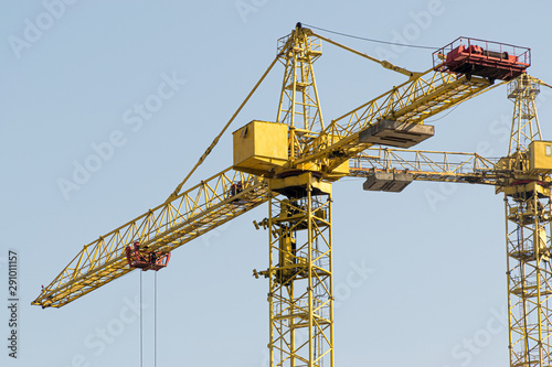 Wallpaper Mural A yellow high-rise building crane against a blue sky builds multi-storey apartment buildings using modern technologies of metal, concrete and brick according to an architectural project Torontodigital.ca