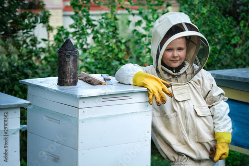 Boy beekeeper in apiary near beehives.Honeycomb with honey. Organic food concept. The most useful organic honey. photo