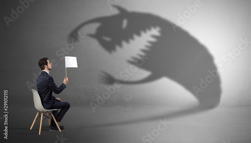 фотографія Young businessman staying and negotiate with a monster shadow
