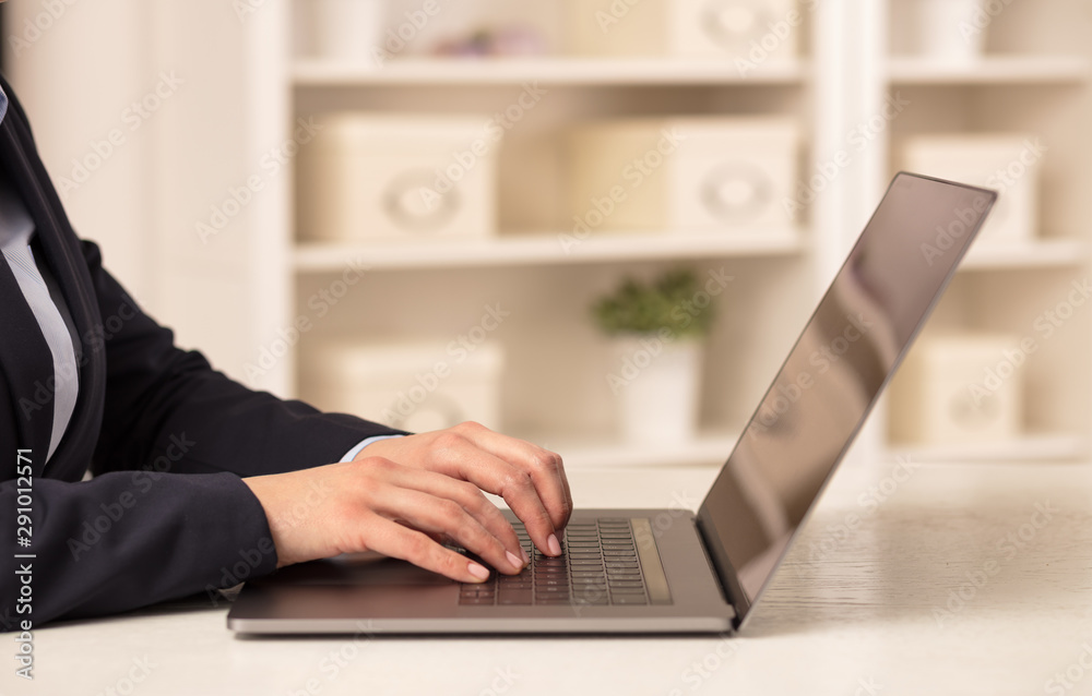 Business woman below chest working on her laptop in a cozy environment Business woman below chest working on her laptop in a cozy environment