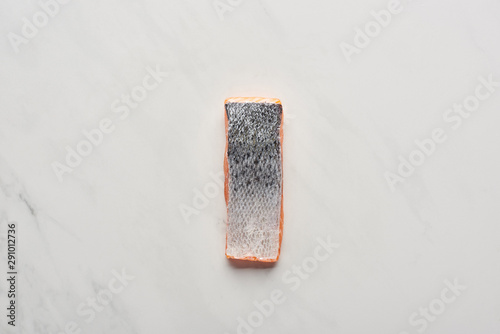 Fototapeta Naklejka Na Ścianę i Meble -  top view of raw fresh salmon steak with fish scales on white marble surface
