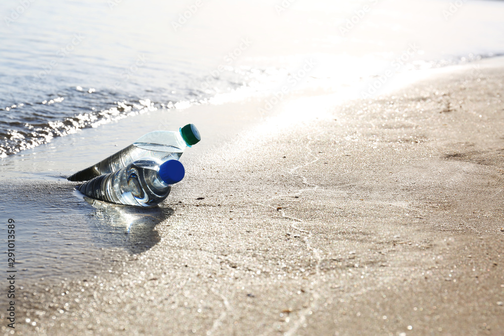 Bottles of refreshing drink in wet sand near sea on hot summer day, space for text Bottles of refreshing drink in wet sand near sea on hot summer day, space for text
