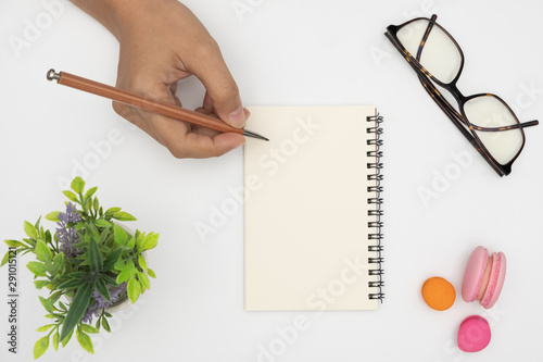 Top view open notebook, pencil, plant potted, glasses and macaro photo