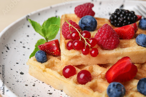 Delicious waffles with fresh berries served on table, closeup