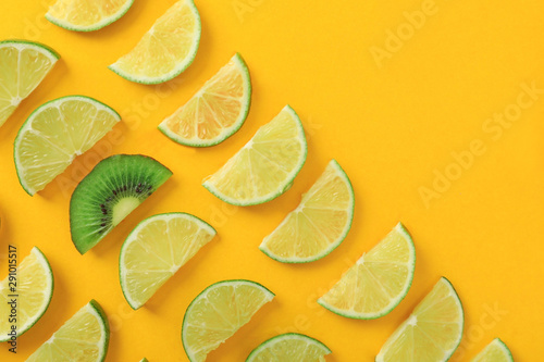 Flat lay composition with slices of juicy exotic fruits on yellow background. Space for text