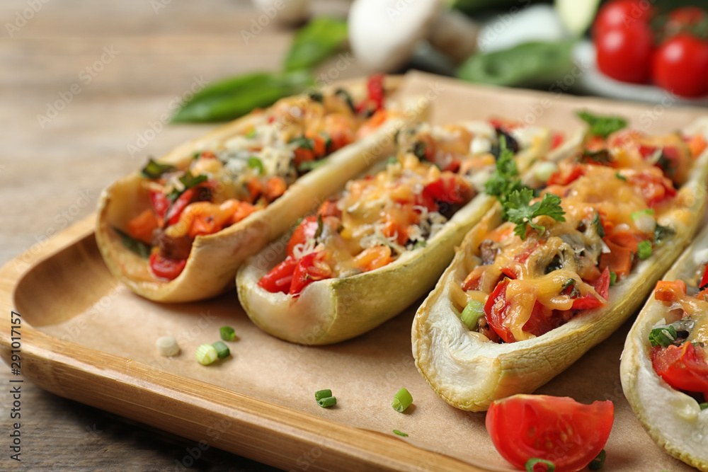 Delicious stuffed zucchini served on wooden table, closeup