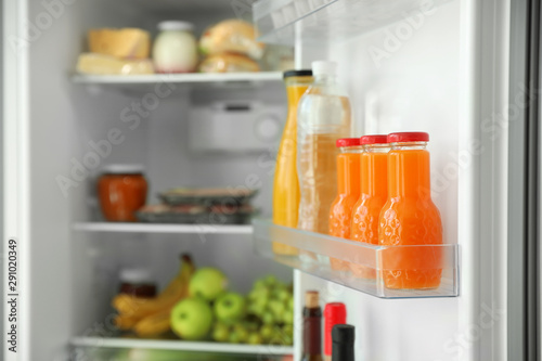 Bottles of juice on shelf in refrigerator
