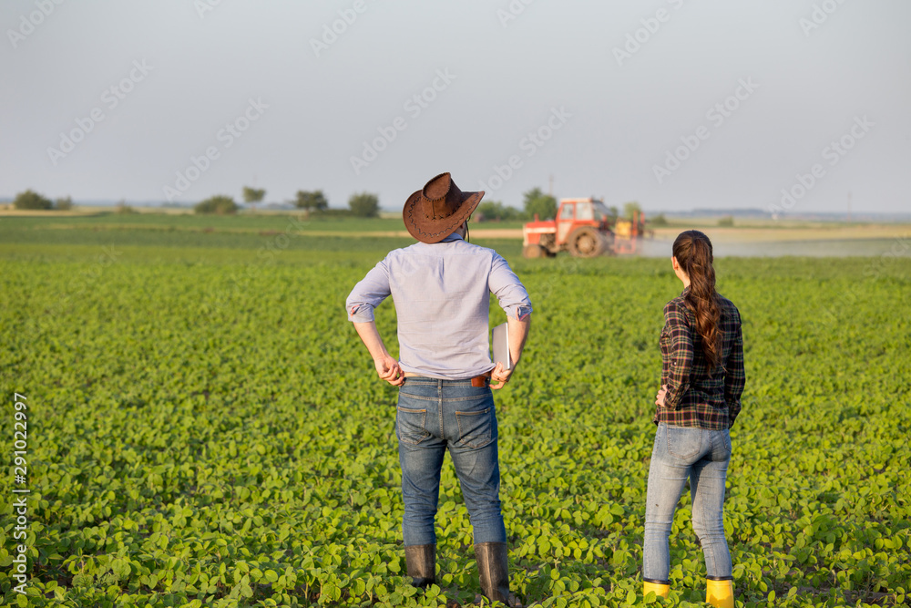 Farmers in front of tractor in field Farmers in front of tractor in field