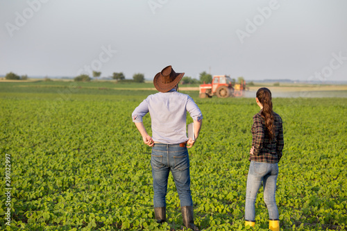 Farmers in front of tractor in field