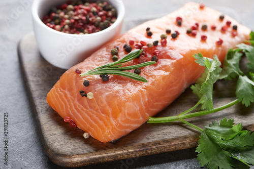 raw salmon with peppercorns, parsley and rosemary on wooden cutting board