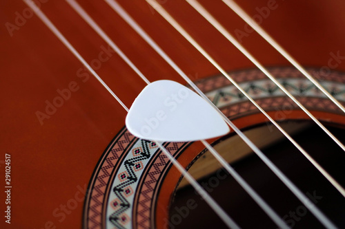 Guitar pick on the fingerboard of a brown guitar. photo