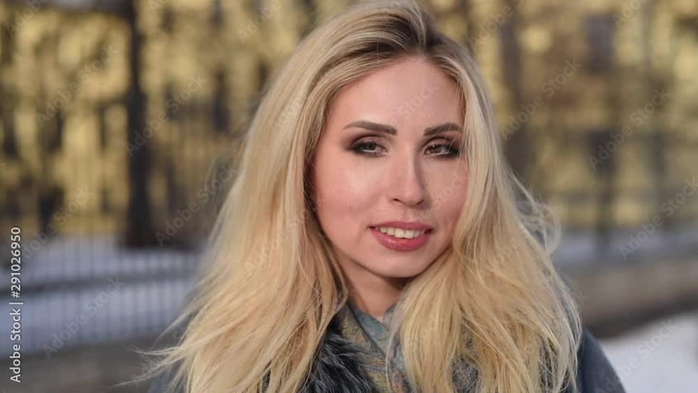 Portrait of beautiful blonde smiling young woman outside enjoying winter snow and sunny day looking at camera, smiling, walking Portrait of beautiful blonde smiling young woman outside enjoying winter snow and sunny day looking at camera, smiling, walking