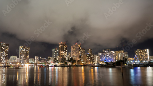 Cityscape of Honolulu at night city lights reflecting in the ocean with low lying fog