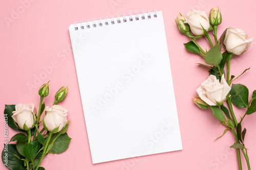 Beautiful white roses flower and notebook on pink background