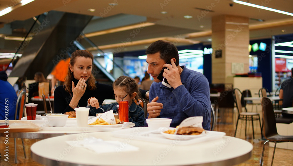 Concept of relaxing family. Father, mother and daughter eating in restaurant.