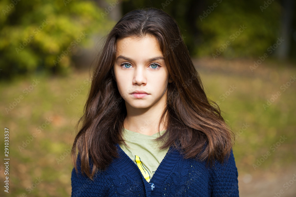 Pretty brunette little girl posing in autumn park background Pretty brunette little girl posing in autumn park background