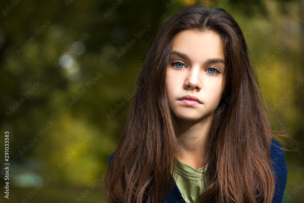 Naklejka premium Pretty brunette little girl posing in autumn park background