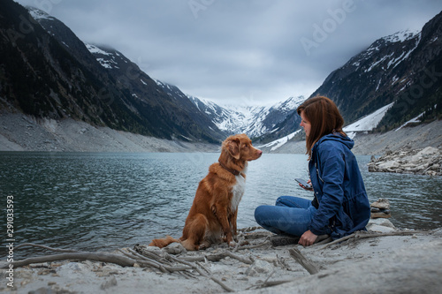 woman with a toller dog at the mountains lake. Traveling with a pet. Nova Scotia Duck Tolling Retriever