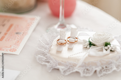 Gold wedding rings on the white rose background