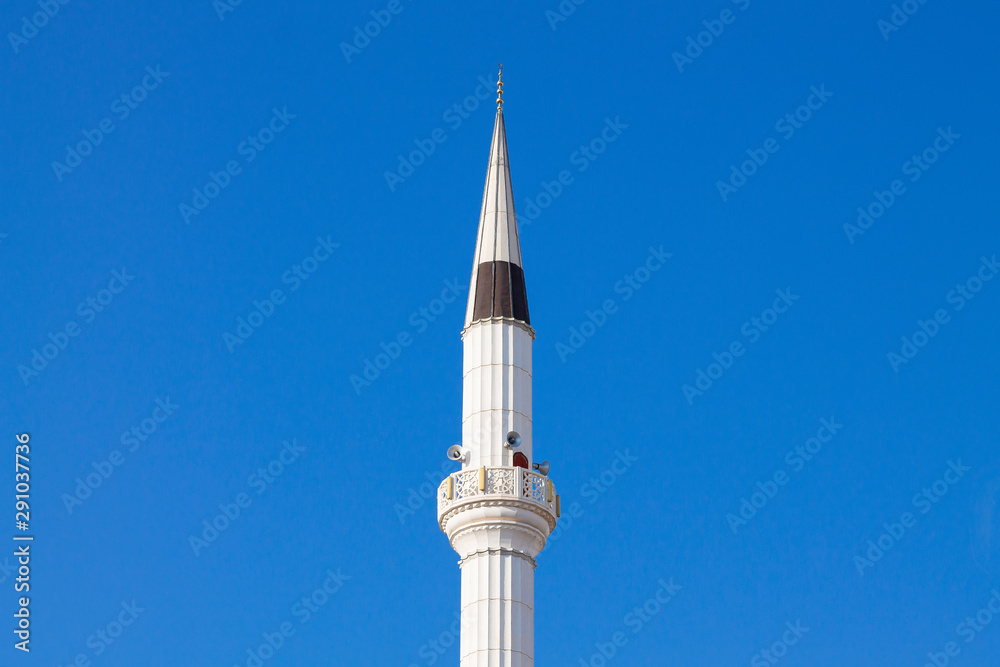 The tower of the mosque minaret against the background of the blue sky. The tower of the mosque minaret against the background of the blue sky.
