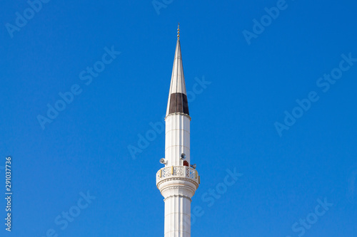 The tower of the mosque minaret against the background of the blue sky.