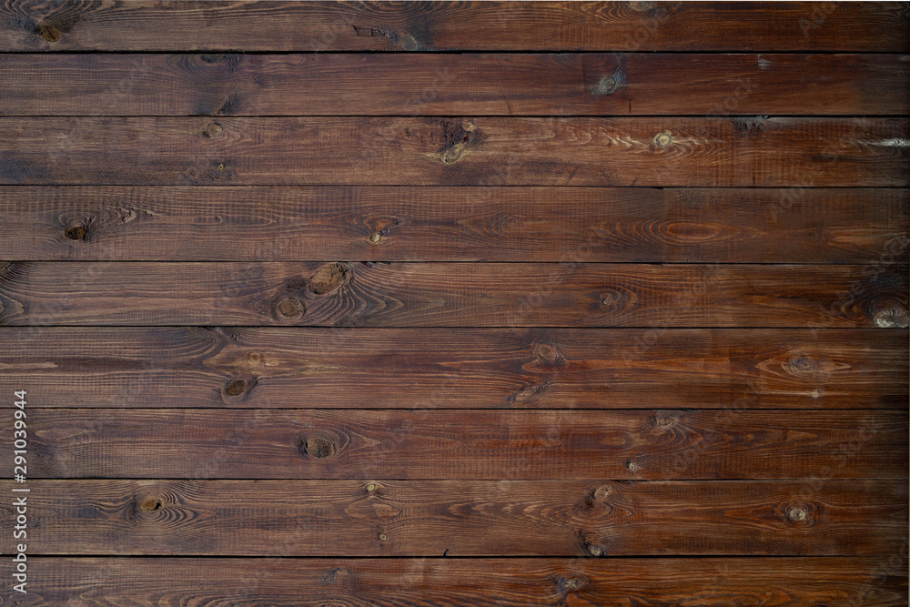 Wooden background of brown boards with retro effect. Wooden fence with natural wear and tear from sun, rain and wind. Beautiful vintage street fence of boards covered with stain and varnish. Wooden background of brown boards with retro effect. Wooden fence with natural wear and tear from sun, rain and wind. Beautiful vintage street fence of boards covered with stain and varnish.
