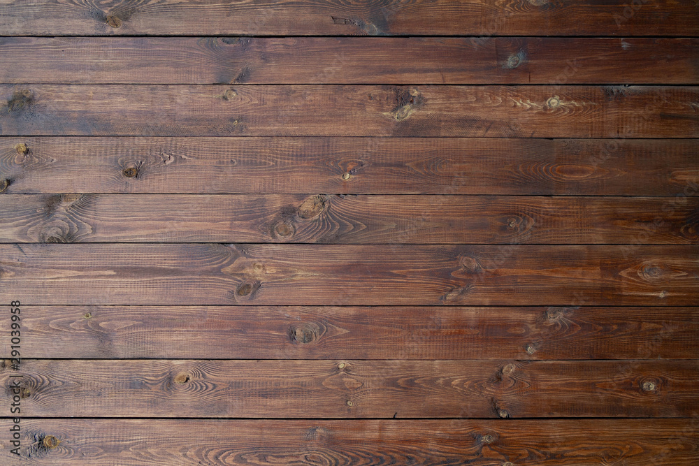 Naklejka premium Wooden background of brown boards with retro effect. Wooden fence with natural wear and tear from sun, rain and wind. Beautiful vintage street fence of boards covered with stain and varnish.