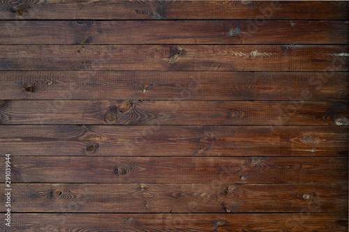 Wooden background of brown boards with retro effect. Wooden fence with natural wear and tear from sun, rain and wind. Beautiful vintage street fence of boards covered with stain and varnish.