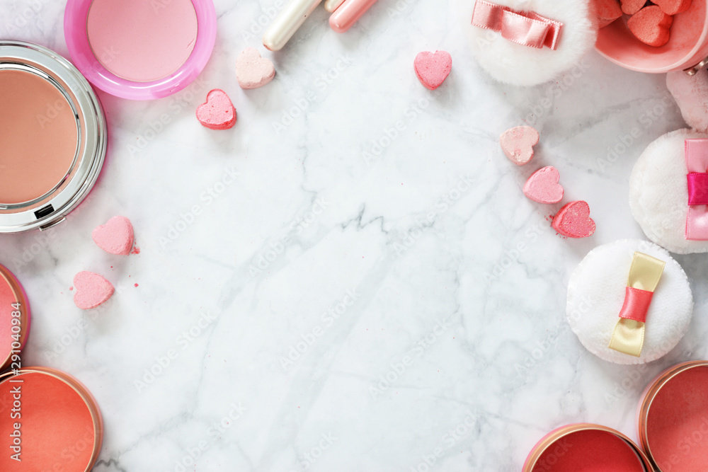 Flat lay on marble background with cute pink beauty products like cute powder puffs with ribbons, blush pots, makeup brushes and pressed powder in heart shape arranged around copy space Flat lay on marble background with cute pink beauty products like cute powder puffs with ribbons, blush pots, makeup brushes and pressed powder in heart shape arranged around copy space