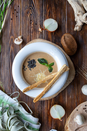 Mushroom soup with pasta with champignons and herbs on a brown wooden background