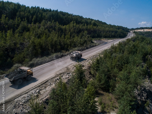Huge industrial dump truck in a stone quarry loaded transporting marble or granite shot from a drone chase