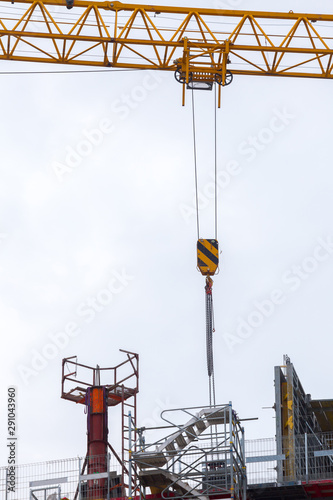 Tower mast crane. Hoisting block with hook on steel chain on the steel rope. Loading\unloading of building materials on construction building site.