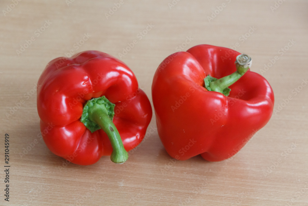 Two whole red peppers on a table Two whole red peppers on a table