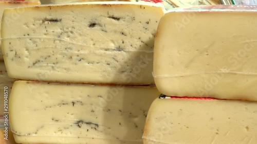 Variety of cheeses displayed in local market. Handheld. Dolly left photo