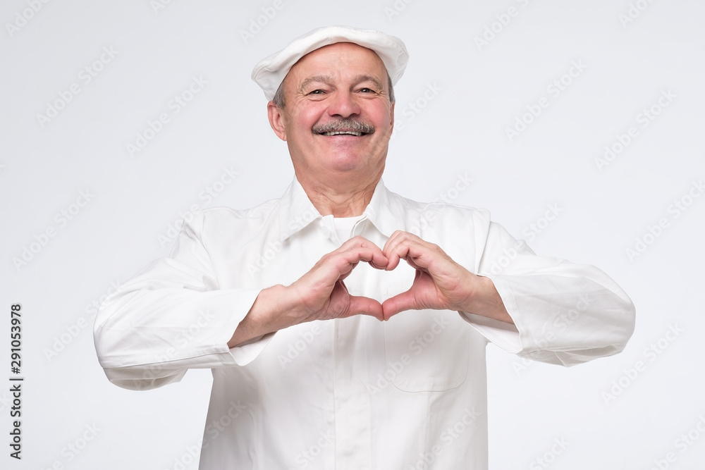 Hispanic caucasian male cook chef in white uniform holding hands in shape of heart, symbolizing love, peace and unity or good health condition. Studio shot Hispanic caucasian male cook chef in white uniform holding hands in shape of heart, symbolizing love, peace and unity or good health condition. Studio shot