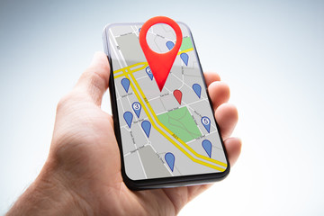 Human Hand Holding Cellphone With Navigation Sign