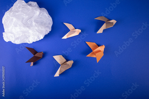 Migration of birds concept of autumn handmade origami birds fly away from the cold on a paper background