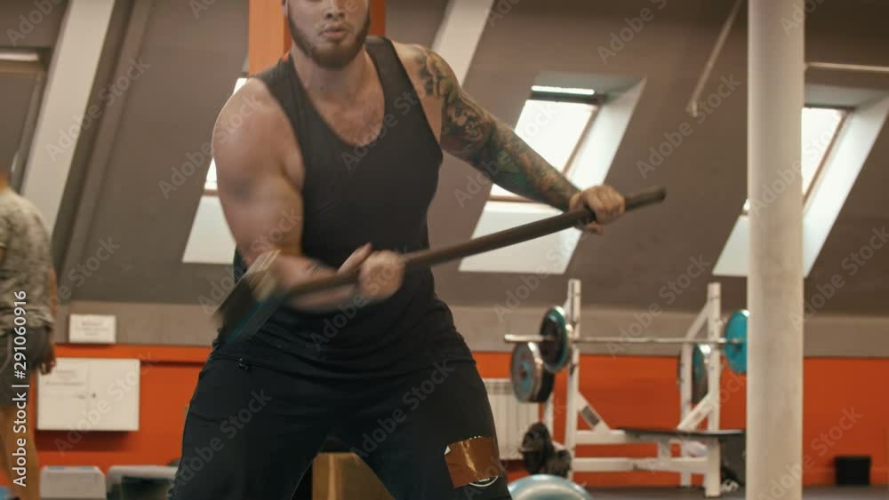A man bodybuilder hitting something with a metal hammer A man bodybuilder hitting something with a metal hammer