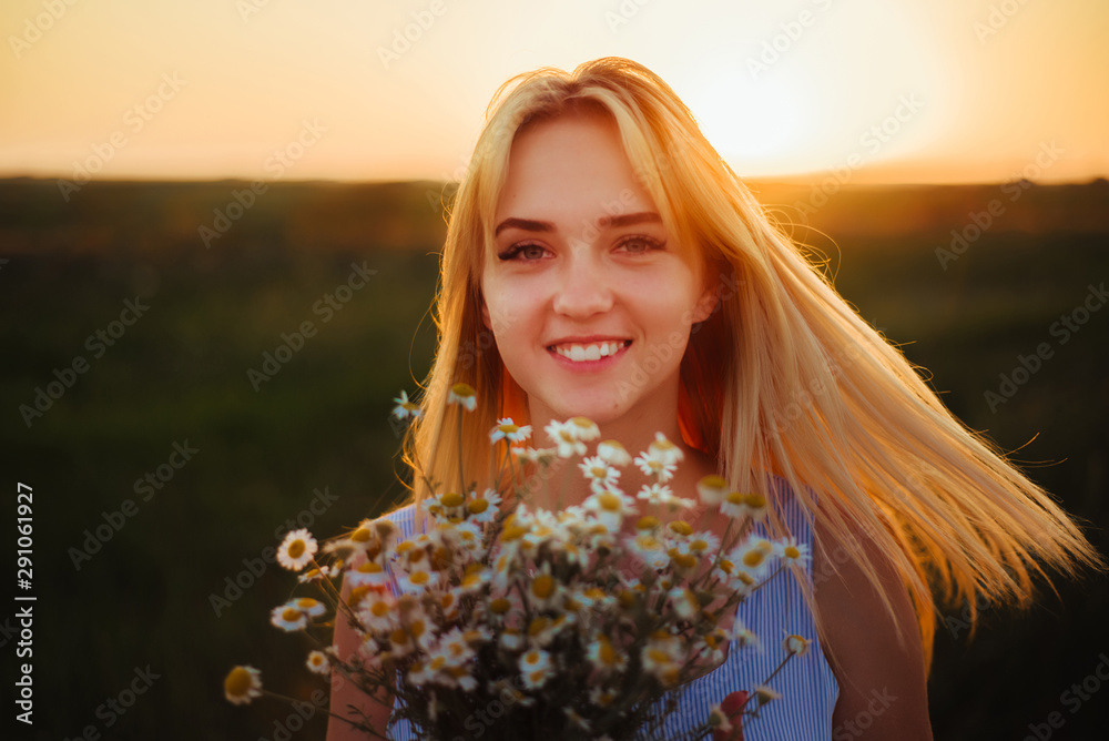 Woman with camomiles smiling on sunset background Woman with camomiles smiling on sunset background
