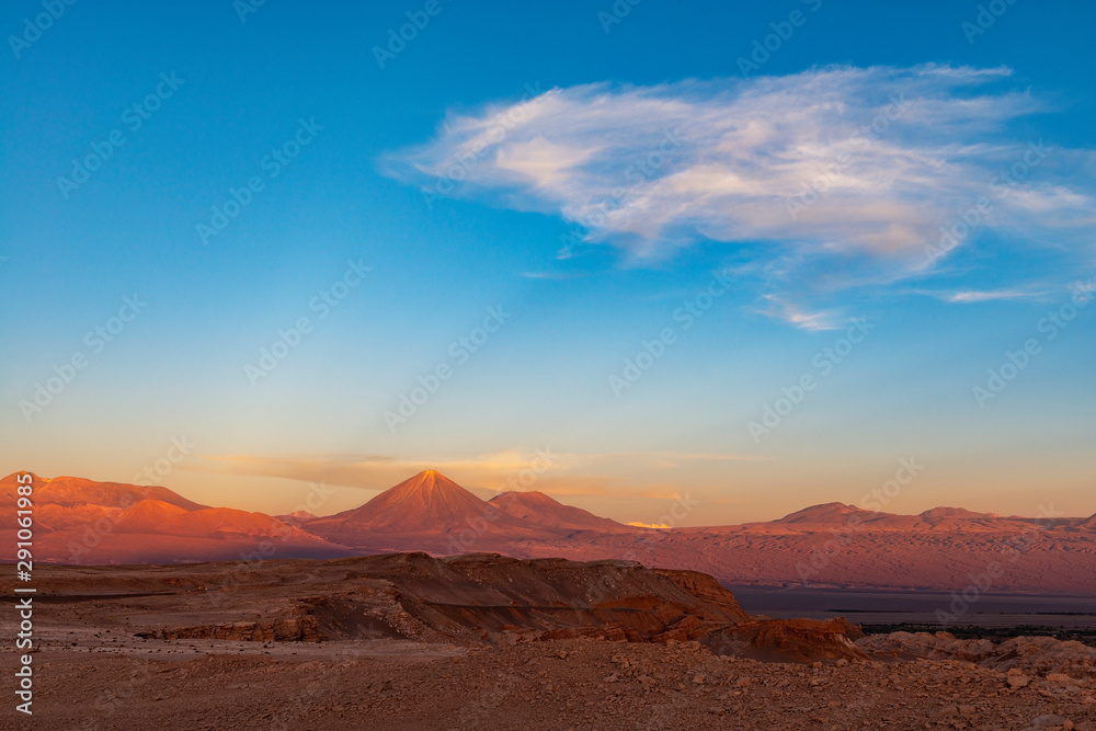 A majestic sunbeam at sunset in the Moon Valley of the Atacama desert with the Licancabur volcano peak, Chile.