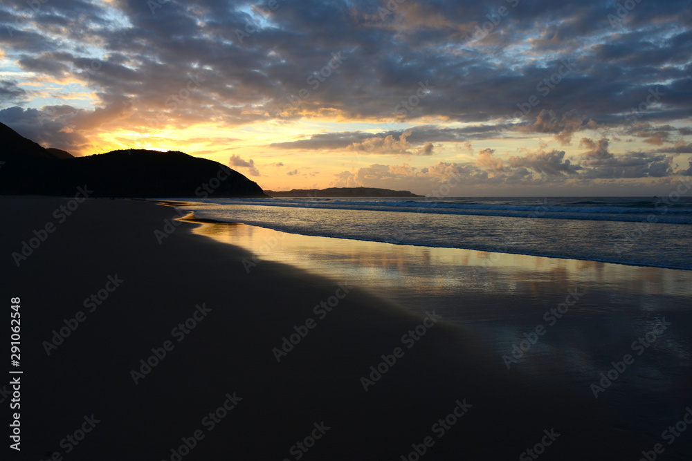 Fototapeta premium empty beach in Portugals Algarve with reflecting clouds in wet sand during sunset