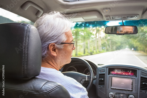 Senior man driving vehicle on narrow road with nature