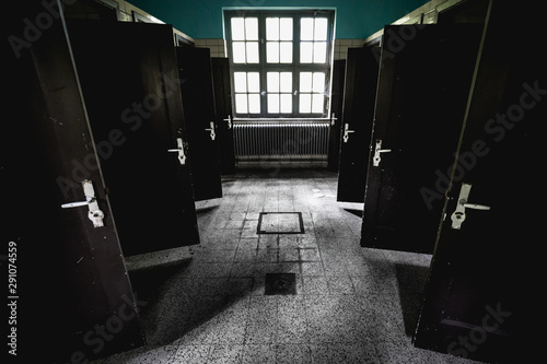 Symmetrical shot of the interior of an abandoned building's bathroom with all doors open photo