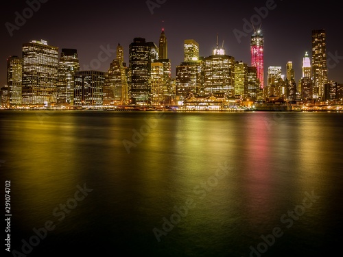Night shot of Manhattan skyline as seen from Brooklyn Heights  with colorful city lights reflecting on water