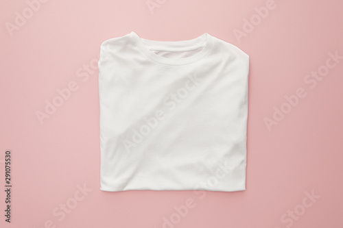 top view of blank white folded t-shirt on pink background