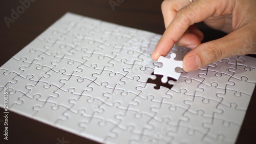 hand pick a piece of jigsaw to connect success on wooden table top selected focus