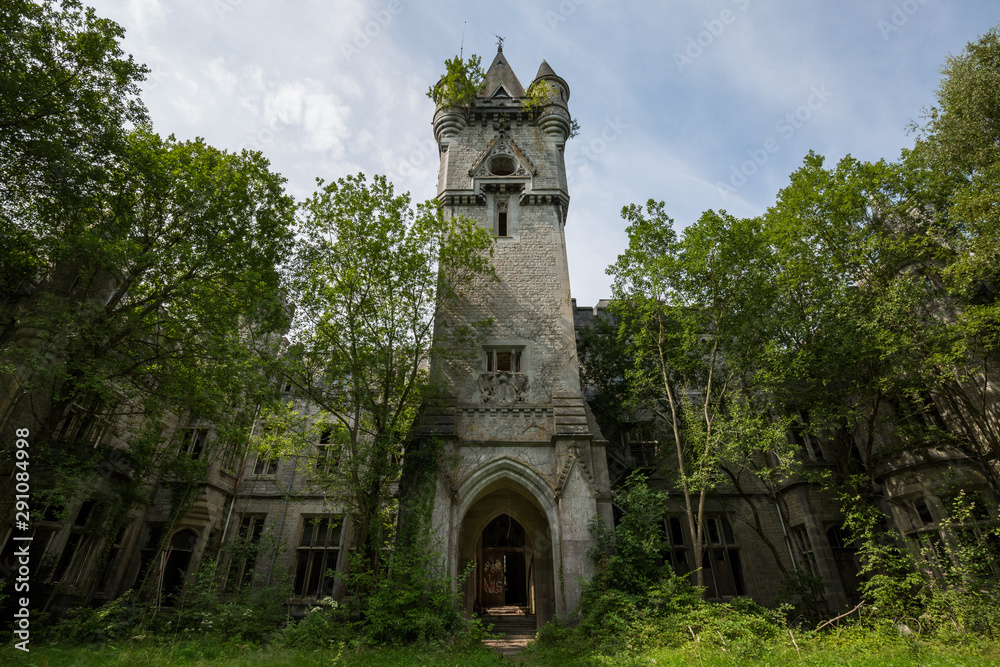 An abandoned and crumbling castle is surrounded by vegetation; the only emerging element is the ancient clocktower